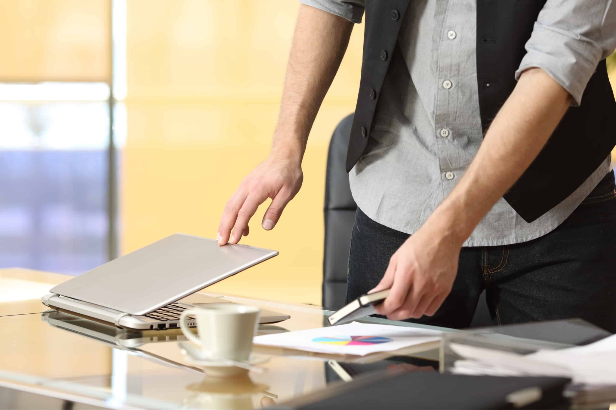 man closing laptop to leave office