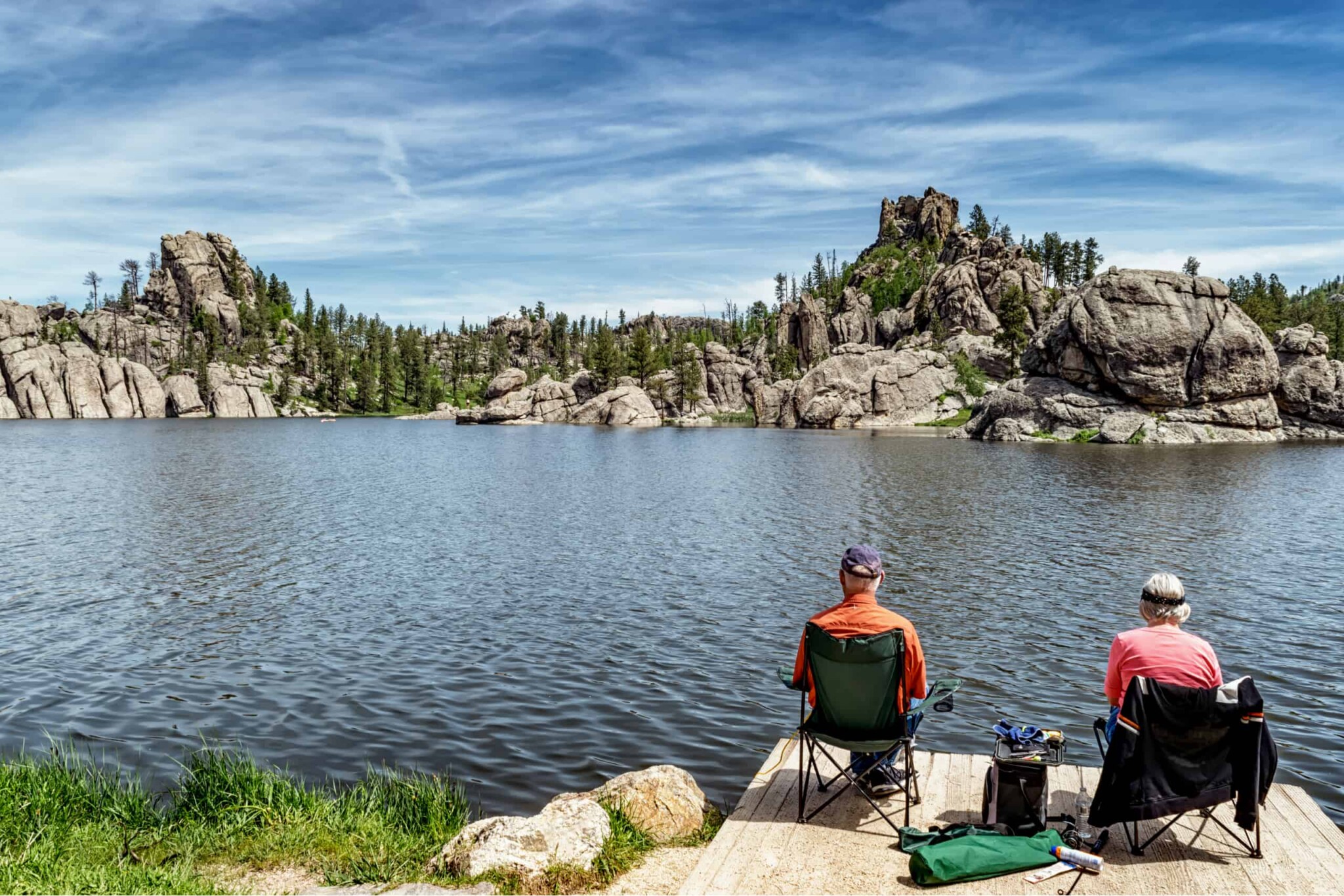 older couple in camping chairs fishing on a lake