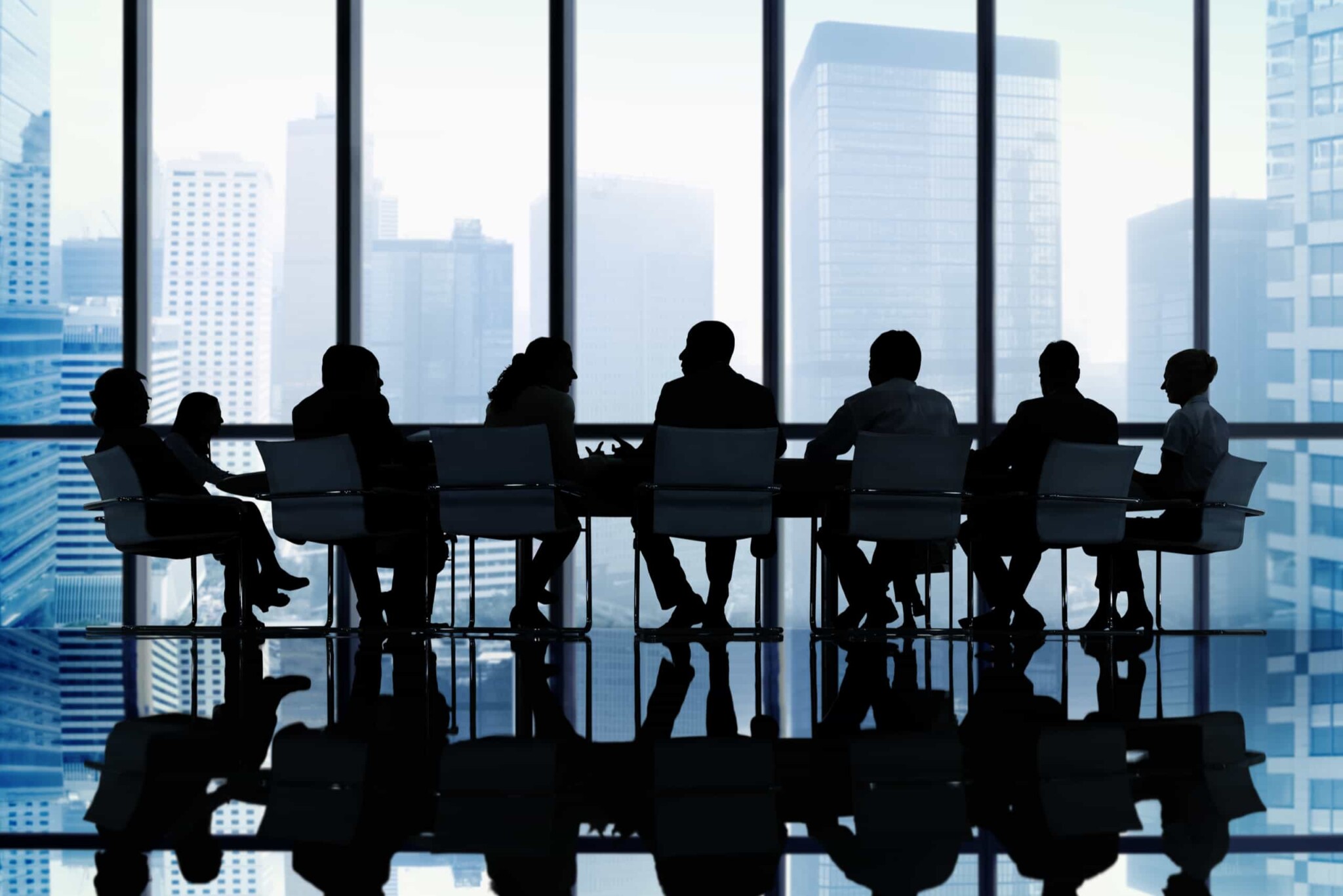 a silhouette of businesspeople at a table in a meeting room