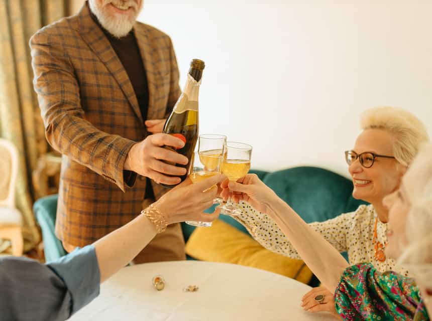 four people celebrating a toast with a bottle of bubbly